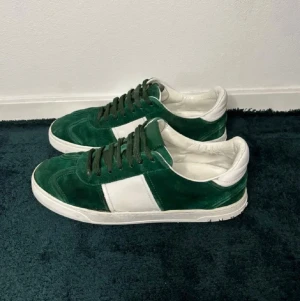Valentino Skor Gröna och vita kombination i mocka - Snygga sneakers i grön mocka med vita detaljer och vita sulor. Skorna har gröna skosnören och en klassisk låg siluett. Perfekta för dig som vill sticka ut med en cool färgkombination. Passar till många olika stilar. Stilrena Valentinos i en unik färg kombination!