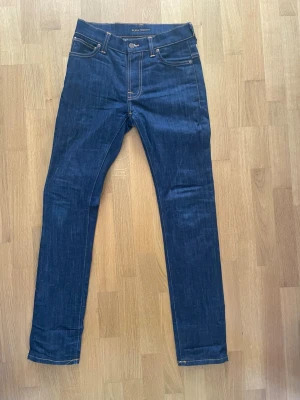 Mörkblå skinny jeans från Nudie - Riktigt feta slim jeans från Nudie Jeans 🔥. Jeansen har en smal passform och är tillverkade i raw  denim för framtida fades. Bakfickorna har Nudies ikoniska broderi. Jag skickar alltid inom 24 timmar 📦
