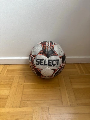 Select Flash Turf fotboll - Säljer en Select Flash Turf fotboll i vitt, svart och rött med geometriskt mönster. Bollen är märkt med 'AG Artificial Grass' och är anpassad för spel på konstgräs. Perfekt för dig som gillar att lira fotboll på planen!