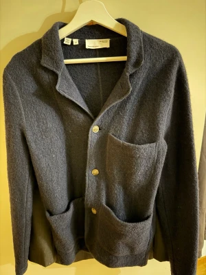 Mörkblå Overshirt  - Mysig mörkblå kofta i ull från selected home med tre knappar framtill och stora utanpåfickor. Klassisk krage och avslappnad passform, perfekt för lager på lager. Enkel men stilren design som funkar till det mesta.
