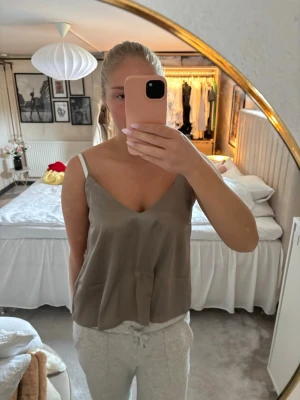 Beige satintopp med v-ringning - Säljer en stilren beige linnetopp med v-ringning och tunna axelband. Toppen har en lös passform och är perfekt för varma dagar. Materialet känns mjukt och svalt mot huden. Köpt för länge sedan så vet tyvärr inte märket🫶🏼