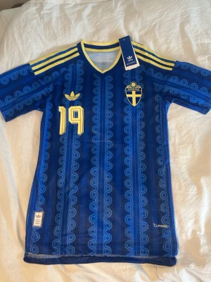 Blå Sverige fotbollströja Adidas - Officiella Sverige bortamatchtröjan  blå  från Adidas med gula detaljer, nummer 19 och Svanberg 