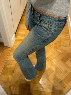 Blå bootcut jeans med låg midja - Snygga blå bootcut jeans med låg midja och klassisk femficksdesign. Jeansen har en lätt tvättad look och är tillverkade i denim med stretch för extra komfort. 