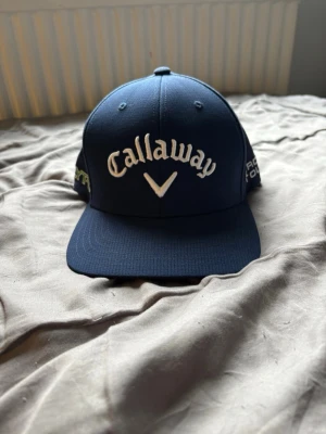 Mörkblå Callaway keps - Mörkblå Golfkeps från Callaway. Riktigt snygg både utanför och på golfbanan. Det är en one size men kan justeras med karborreband. Har använts lite men inget synligt.