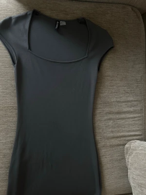 Svart kort klänning från Divided - En svart, tight kortklänning från hm med fyrkantig ringning och ärmlös design. Tillverkad i mjuk och stretchig bomullsblandning som sitter snyggt på kroppen. 