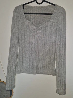 Ribbstickad tröja - Mysig ljusgrå ribbstickad tröja med lång ärm och snygg v-ringning. Tröjan har en smickrande passform och är tillverkad i ett mjukt, stretchigt material som känns skönt mot huden. Perfekt att matcha med jeans eller kjol.