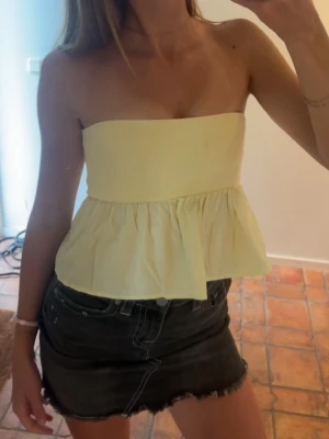 Gul bandeau topp Zara - Bandeau topp i ljusgul färg med volang nedtill från Zara💛 (liten fläck framtill, de sista slide) inget som syns på fest dock🤪Sjölv använt på  fest eller midsommar och passar super bra med många nederdelar! 
