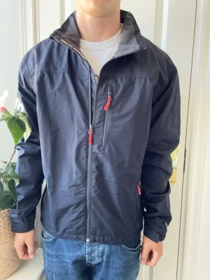 Helly Hansen vindjacka - På plick Live 11 Juni 17.00  - Helly Hansen vindjacka, stor på modellen. Inga defekter! Modellen i bilderna är 180 cm 75 kg och bär Storlek L , Kom med frågor! 🌟 (Kan gå ned i pris vid köp av paket 😉) 