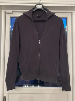 Mörkgrå ziptröja från Massimo Dutti - Stilren mörkgrå ziptröja från Massimo Dutti med hög krage och hel dragkedja framtill. Tröjan har ribbade muddar vid ärmslut och nederkant samt två sidofickor. Perfekt för lager-på-lager och enkel att matcha med olika outfits.