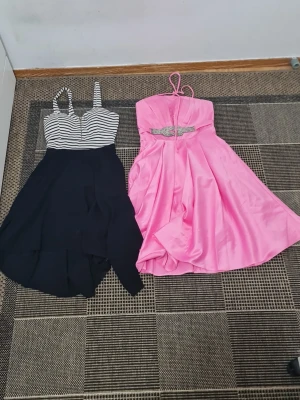 Två korta klänningar, randig & rosa - Båda för 100kr Säljer två snygga kortklänningar. Ena är svart med vit-randig överdel och breda axelband, andra är rosa i glansigt material med smala axelband och dekorerat midjeband med strass. Perfekta för sommarens tillfällen!