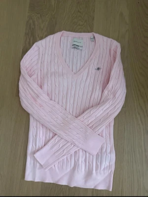 Ljusrosa kabelstickad tröja Gant - Säljer en ljusrosa kabelstickad tröja från Gant i bomull. Tröjan har V-ringning, långa ärmar och en liten broderad logga på bröstet. Perfekt för dig som gillar klassisk och stilren design med en mjuk känsla. Tröjan är helt ny och oanvänd😇Passar storlekerna S-M 