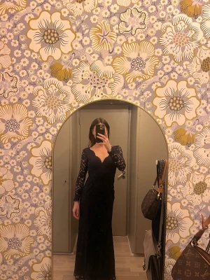 Malina marinblå lång spetsklänning - Malina marinblå långklänning med v-ringning och långa spetsärmar. Klänningen har figurnära passform och är helt täckt av vacker spets. Passar bal och bröllop. Använd en gång på ett bröllop, storleken är S och klänningen saknar fästet till lilla kroken ovan dragkedja i rygg. Annars perfekt skick. 