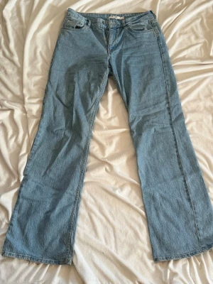 Ljusblå raka jeans med hög midja - Säljer ett par ljusblå jeans med rak passform och mid waist midja. Klassisk femficksmodell och dragkedja med knapp. Jeansen har en avslappnad look och är tillverkade i denim, perfekt för en casual stil. NAKD 