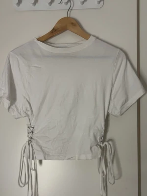 Vit croppad t-shirt med snörning - Säljer en vit croppad t-shirt från Miss Selfridge med korta ärmar och snygg snörningsdetalj i sidorna. Det står ej någon strl på lappen. Men den passar mig som har XS-S i toppar!! Skriv om ni vill ha mer info💕💕