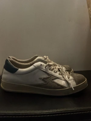 Vita MoaConcept sneakers  - Säljer ett par vita sneakers med grå mockadetaljer. Köpta för 2600 på NK och är använda hyfsat mycket.