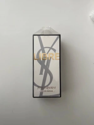 YSL Libre EdP 90 ml - Yves Saint Laurent Libre Eau de Parfum i elegant vit och svart förpackning med guldtext. Doften är känd för sin fräscha och blommiga karaktär, och flaskan har en lyxig design som känns modern och stilren. Perfekt för dig som vill ha en ikonisk parfym från ett exklusivt märke.