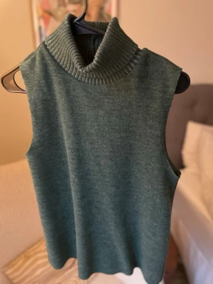 Grön ärmlös polotopp - Mysig grön polotopp i stickat material med hög krage och ärmlös design. Perfekt att styla med jeans eller kjol för en trendig look. Tidlös och enkel att matcha med olika outfits.☺️