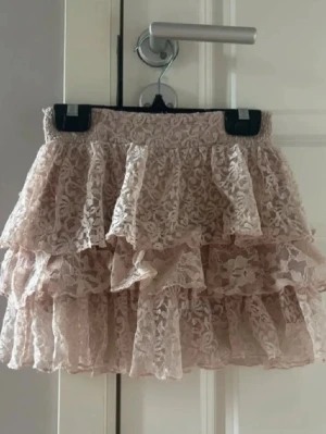 Beige/rosa spetskjol med volanger - Supersöt beige kortkjol i spets med flera lager volanger. 