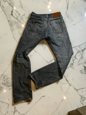 Levis 501 Jeans  - Levi’s jeans i blå tvätt, storlek 28/32. Klassisk 5-pocketmodell med rak passform. Använt skick med mindre slitningar och märken som syns på bilderna. Säljes som de är.
