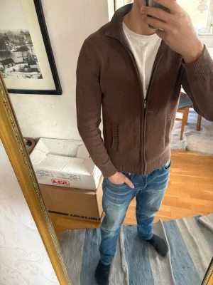 Brun stickad ziptröja från Dressmann - Säljer en brun stickad ziptröja från Dressmann. Skicket är fortfarande väldigt bra, det är endast en liten defekt vid ena fickan, som inte märks av överhuvudtaget. Nypris 700 kr, mitt pris 350 kr.