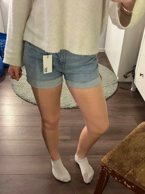 Blå denimshorts från lager 157 - Säljer ett par klassiska blå denimshorts från lager 156. Shortsen har upprullade benslut, femficksmodell och normal passform. Perfekta till sommaren och lätta att matcha med olika toppar.