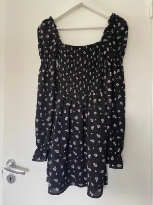 Svart klänning med lila blommor - Klänning, inte använt så mycket så är i bra skick skulle jag säga! Lite mindre i storleken skulle jag säga då den är från H&M divided (för ungdomar typ). 