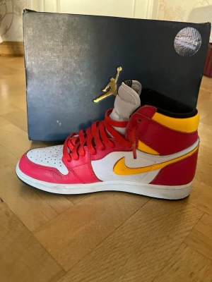 Nike Air Jordan 1 High röd/gul/vit - Priset går att förhandla. Använda ett fåtal gånger med ett nypris runt $150 vid köpet.  Snygga Nike Air Jordan 1 High sneakers i rött, vitt och gult med klassisk siluett. Skorna har röda snören, vit tåbox med perforeringar och gul swoosh. Ovandelen är i läder och insidan är svart. Perfekta för dig som vill sticka ut med färg och stil.