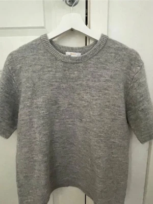 Stickad T-shirt  - Ljusgrå stickad T-shirt från Gina Young, strl 158/164. Den ser lite mörkare ut på en bild  men är ljusgrå.