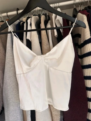 Vit siden topp - Vit siden-topp. Materialet känns mjukt och lätt, perfekt för varma dagar. Köpt här på plick och är i bra skick