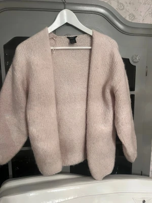 Beige/vit stickad kofta från Lindex - Mysig beige/vit stickad kofta från Lindex i oversized modell. Koftan har öppen front utan knappar och är gjord i ett fluffigt, mjukt material. Perfekt att slänga över en t-shirt eller topp för extra värme.