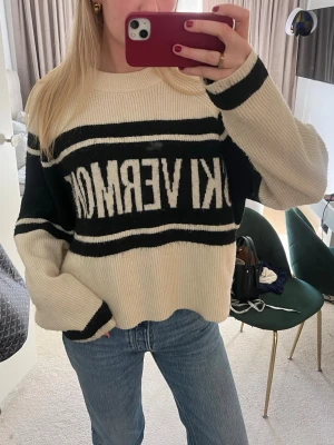 Beige och svart stickad tröja - Trendig stickad tröja i beige och svart med breda ränder och texten 'SKI VERMONT' framtill. Lite nopprig💗