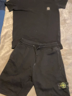 Svarta shorts från Stone Island - Säljer ett par svarta shorts från Stone Island med klassisk patch på benet. Shortsen har dragsko i midjan och sidofickor. Perfekta för en avslappnad och stilren look. Materialet känns mjukt och bekvämt, troligen bomull.