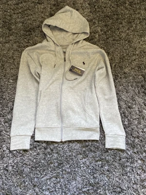 Grå ralphlauren zip hoodie  - Sprillans ny hoodie från ralphlauren, säljer för att den inte passade. Perfekt för chill kvällar hemma eller att ha ute 