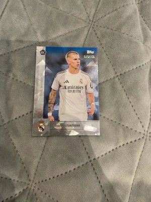 Topps Real Madrid samlarkort - Samlarkort från Topps med Real Madrid-tema, visar Franco Mastantuono i vit matchtröja. Kortet har silverfärgade detaljer och är numrerat 07/150. Perfekt för dig som gillar fotboll och samlar på sportkort.