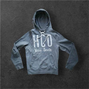 Unik Hollister Hoodie! - Snygg grå hoodie från Hollister med stor vit HCO-logga och texten 'Wave Devils' på bröstet. Hoodien har huva med dragsko och en klassisk känguruficka framtill. Perfekt för en avslappnad och cool stil.