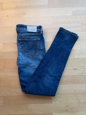 Jacob Cohën Slim Fit Jeans - Jacob Cohën slim fit jeans i marinblå. Mycket bra skick, använda ett fåtal gånger och har ett mycket bra helhetsintryck. Mått: midja ca 41 cm, längd ca 104 cm. Material: 99% bomull, 1% elastan. Säljes som de är. Skickas välpackade inom 24 timmar.