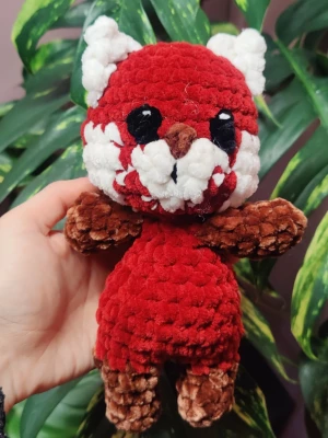 Handgjord röd panda amigurumi - Supergullig handvirkad amigurumi i form av en röd panda. Gjord av mjukt, fluffigt garn i rött, vitt, brunt och svart. Stora svarta ögon, vit nos och öron samt brun svans och tassar. Perfekt som present eller dekoration.