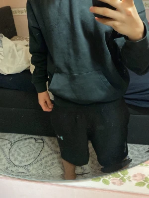 Svart Essentials hoodie med huva - Säljer en svart hoodie från Essentials med broderad logga på bröstet. Hoodien har en klassisk känguruficka framtill och en stor huva. Tillverkad i mjukt bomullsmaterial som är skönt att bära. Perfekt för en avslappnad och stilren look.