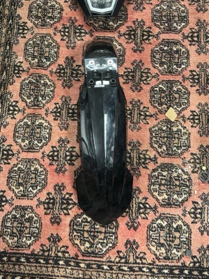 Ktm lampa+ ktm stänka 125 - Säljer en svart plastskärm som passar till elscooter eller elcykel. Skärmen har en blank finish och är formad för att skydda mot stänk från hjulen. Monteringshål och fästen finns på ovansidan. Perfekt för dig som behöver en reservdel.