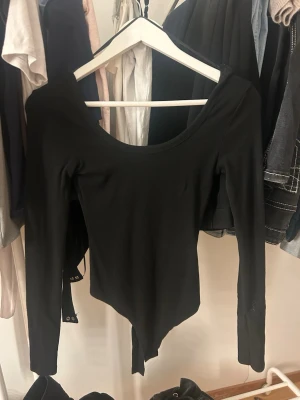 Svart långärmad body - Säljer en svart långärmad body med rundad urringning. Bodyn har en enkel och stilren design med tryckknappar i grenen. Perfekt att styla till olika outfits och passar till både jeans och kjol.