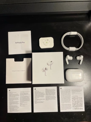 Apple AirPods Pro trådlösa hörlurar - Säljer ett par vita Apple AirPods Pro med laddningsetui, originalkartong, laddningskabel och extra öronproppar. Hörlurarna har en stilren och kompakt design i plast och silikon, perfekt för dig som vill ha grymt ljud och brusreducering. Allt originaltillbehör medföljer.