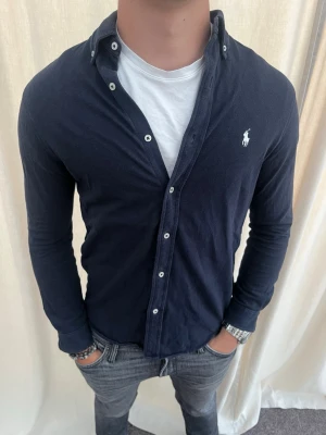 Marinblå skjorta från Ralph Lauren - Riktigt snygg skjorta från Ralph Lauren. Strl S, personen på bilden är 185 cm lång. Skicka gärna prisförslag. Kika in min profil för mer schyssta plagg