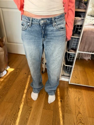 Ljusblå baggy jeans med raka ben - Säljer ett par ljusblå baggy jeans med raka ben och klassisk femficksmodell. Jeansen har en avslappnad passform och är tillverkade i denim med slitna detaljer. Perfekta för en casual och trendig look. Modell arrow 