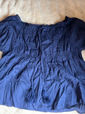 Blå offshoulder blus med tofsar  - Off shoulder blus från Nelly, ny utan prislapp 
