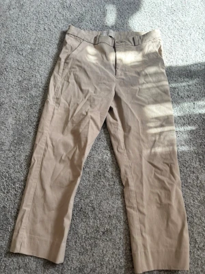 Beige chinos från Freequent XS - Snygga beige chinos från Freequent i storlek XS. Klassisk rak passform med bälteshällor, knapp och dragkedja framtill. Tillverkade i ett mjukt och lätt material som passar perfekt till en avslappnad stil. Enkla att matcha med både t-shirt och skjorta.