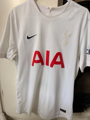 Nike Vit Tottenham Hotspur som ny - Säljer en vit Tottenham Hotspur matchtröja från Nike med klubbmärke och sponsorlogga AIA i rött på bröstet. Tröjan har korta ärmar, V-ringning och är tillverkad i ett lätt, ventilerande funktionsmaterial. Perfekt för fotboll eller träning.