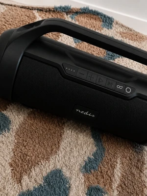 Svart bärbar högtalare från Nedis - Snygg svart bärbar högtalare från Nedis med robust handtag och tydliga knappar för volym, play/pause och mode. Högtalaren har en modern, cylindrisk form och är klädd i slitstarkt tygmaterial. Perfekt för att ta med sig musiken överallt.