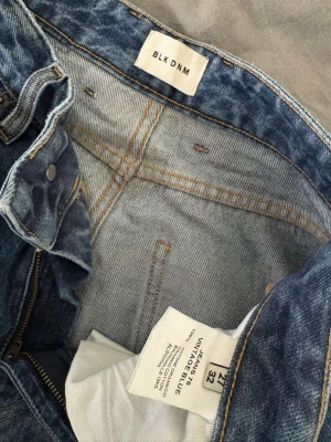 BLK DNM vintageblå jeans - Säljer ett par jeans från BLK DNM i vintageblå tvätt. Jeansen har hög midja, klassiska fem fickor och markerade pressveck framtill. Tillverkade i 100% ekologisk bomull för en autentisk denimkänsla. W27L32