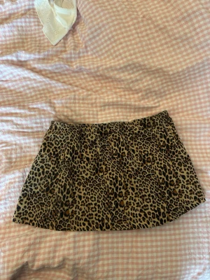 Leopardmönstrad kortkjol - Leopardkjol med tillhörande bälte.Snygg kortkjol med leopardmönster i bruna och svarta toner. Kjolen har en rak passform och är perfekt för dig som vill sticka ut med en trendig look. Materialet känns mjukt och följsamt, vilket gör den bekväm att bära hela dagen.