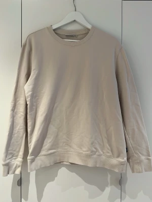 Beige sweatshirt från Dobber - Stilren beige sweatshirt från Dobber med rund halsringning och ribbade muddar vid ärmslut och nederkant. Tröjan har en avslappnad passform och är tillverkad i mjukt bomullsmaterial. Perfekt för en clean och enkel look.